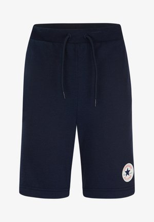 Bermudas de algodão azul marinho com cintura elástica e cordão, apresentando um emblema redondo da Converse All Star na perna esquerda.