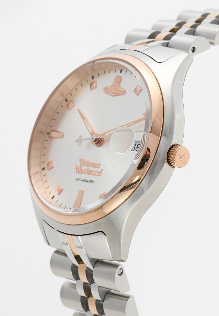 Srebrny i różowo-złoty zegarek z okrągłą tarczą, białą powierzchnią, diamentowymi znacznikami oraz stalową bransoletą z różowo-złotymi akcentami. Szwajcarski mechanizm.