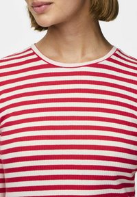 Röd- och vitrandig ribbad topp med rund halsringning och textilstruktur. Inga ytterligare mönster eller detaljer synliga.