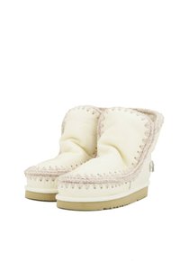 Stivali alla caviglia in pelle bianca con una texture morbida, caratterizzati da un design cucito distintivo in beige chiaro e una punta arrotondata.