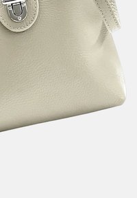 Beige leren handtas met een gladde textuur, voorzien van een ronde sluiting en gestikte accenten. Rechthoekige vorm met zachte randen.