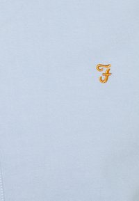 Polo shirt azzurro chiaro realizzato in cotone; presenta un piccolo logo ricamato giallo "F"; texture liscia con un design del colletto classico.