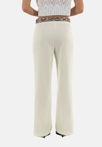 Pantaloni bianchi a gamba larga con una vita in tessuto a stampa serpente testurizzata, caratterizzati da una finitura in tessuto liscia e linee pulite.