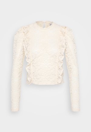 Crop top en dentelle crème avec des manches longues, des détails froncés sur les côtés et un col haut avec une fermeture en gouttière au dos.