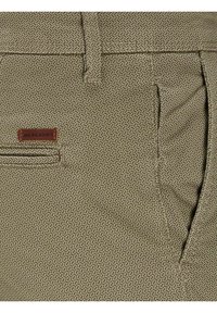 Shorts in tessuto beige con motivo geometrico testurizzato, dotati di una tasca laterale e di un'etichetta in pelle marrone.