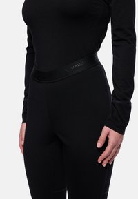 Leggings de sport noirs avec une texture lisse et une large taille de marque. Présente un design ajusté et des détails de couture visibles.