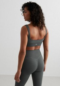 Donkergroen geribbeld activewear set met een aansluitende sportbeha met brede bandjes en hoog getailleerde leggings, die een gestructureerde stof tonen.