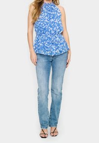 Modrý top na zavazování s peplum lemem, doplněný o světle modré rovné džíny a černé sandály na podpatku. Hladká látka, přiléhavý střih.