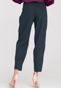 Marynarskie spodnie o tapered fit, z bocznymi kieszeniami, subtelnymi detalami w szwie i średnim stanem, zestawione z jasnokolorowymi szpilkami.