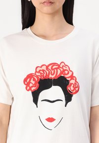 Bijela majica s grafičkim printom lica crne kose i crvenih ruža. Dizajn uključuje debele crne linije i jednostavne crte lica.