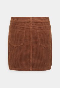Bruine corduroy rok met een gestructureerd oppervlak, met een aansluitende taille, twee achterzakken en horizontale geribbelde patronen.