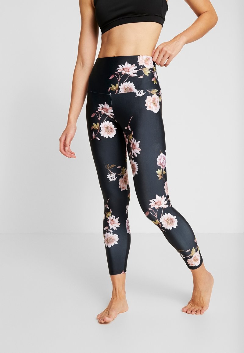 Zwarte bloemenleggings met een hoge taille, een gladde textuur en een levendig roze bloemenpatroon dat de zijkanten accentueert.