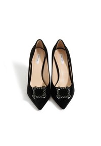 Czarne zamszowe szpilki z spiczastymi noskami, z prostokątną czarną klamrą z cyrkoniami na wierzchu i gładkim beżowym wnętrzem.