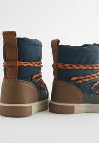 Blauwe gewatteerde laarzen met oranje veters en bruine rubberen zolen. Het ontwerp heeft een hoge kraag en gestructureerde accenten bij de hak.
