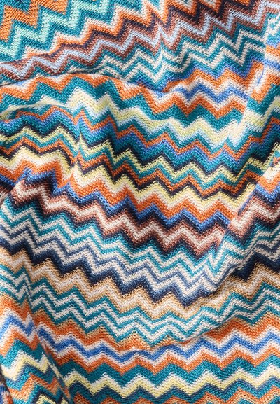 Πολύχρωμο πλεκτό ύφασμα με ζιγκ-ζαγκ σχέδια σε μπλε, πορτοκαλί, καφέ, κίτρινο και κρεμ χρώμα, που δείχνει υφή και ριχτά πτυχώσεις.