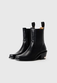 Bottines en cuir noir avec des panneaux latéraux élastiques, un design épuré et un talon empilé avec un accent métallique. Texture lisse, bout pointu.