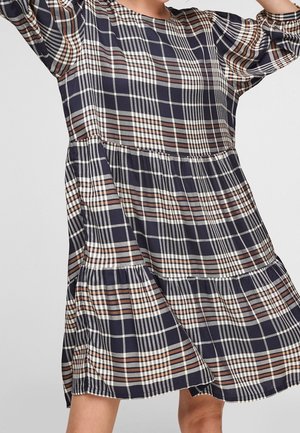 Granatowa sukienka w kratę z długimi rękawami, okrągłym dekoltem i warstwowym krojem z kontrastującymi białymi i brązowymi paskami.