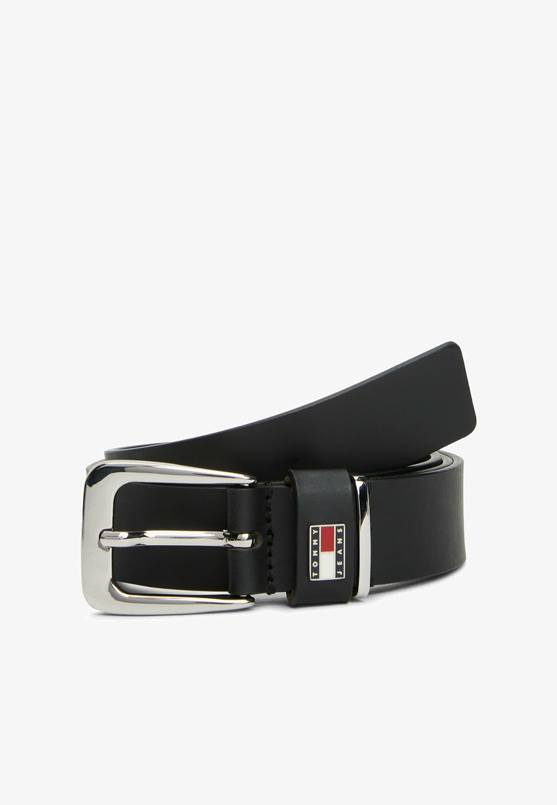 Cinturón de cuero negro con un diseño ancho, que cuenta con una hebilla rectangular de plata brillante. Se ha añadido un parche con el logo cerca de la hebilla.