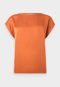 Blouse orange à manches courtes avec revers roulés et col rond haut, présentée sur un fond gris clair uni.