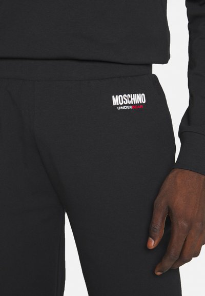 Black cotton sweatpants featuring a white and red "MOSCHINO UNDERBEAR" logo on the leg. Smooth texture, elastic waistband for comfort.