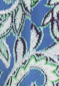 Motif floral abstrait bleu, vert, noir et blanc sur tissu tissé avec texture visible et une couture verticale centrale.