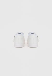 White leather sneakers with smooth finish, low-top design, round toe, and flat rubber soles. Accented with subtle branding on the heel.