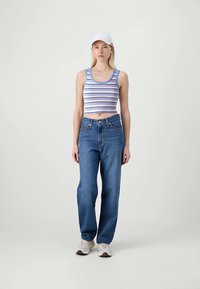 Prugasti cropped top u plavoj, ljubičastoj i bijeloj boji; hlače visoki struk u plavoj boji; bijela kapa; neutralne trenirke; glatka tkanina; opušteni kroj.