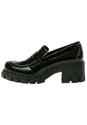 Mocassin noir à talon épais avec semelle à crampons épaisse et une lanière sur le cou-de-pied, en cuir brillant.