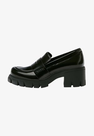 Mocassin noir à talon épais avec semelle à crampons épaisse et une lanière sur le cou-de-pied, en cuir brillant.