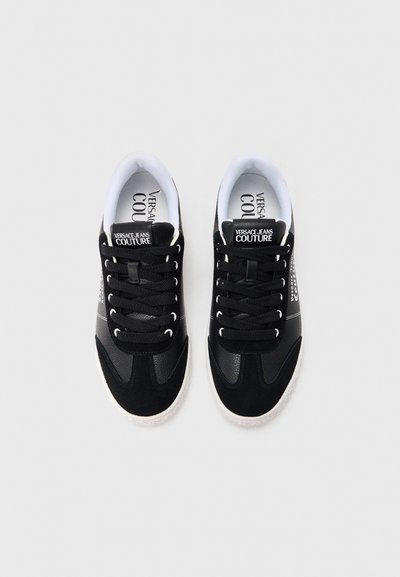 Чифт черни маратонки Versace Jeans Couture с бели подметки и връзки, гледани отгоре на бял фон.