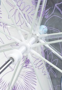 Primo piano delle stecche bianche di un ombrello e dell'asta centrale, con una copertura trasparente decorata con motivi floreali viola e linee a mano.