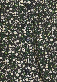 Schwarzes Stoffhemd mit einem floralen Muster aus weißen und gelben Blumen sowie grünen Blättern. Verziert mit schwarzen Knöpfen, die vertikal angebracht sind.