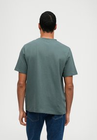 T-shirt κοντομάνικο, με στρογγυλή λαιμόκοψη σε μουτζουρωμένο πράσινο, από βαμβάκι, με ευθύ κοψίμα και απαλό υφή, όπως φαίνεται από πίσω.