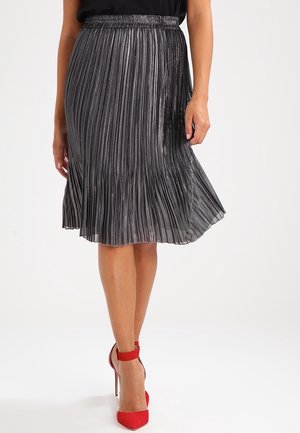 Metallic pleated midi skirt in dark gray, featuring a gathered waistband and flowing hemline. Paired with red high-heeled shoes.
