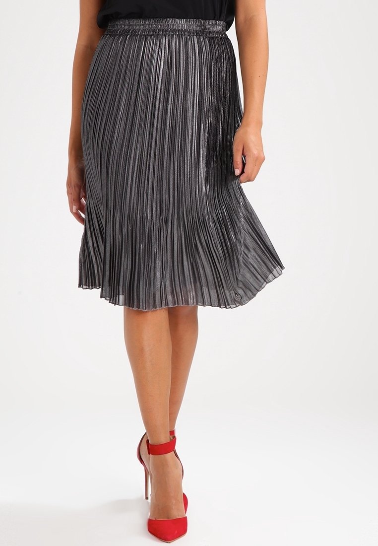 Metaliczna plisowana spódnica midi w ciemnoszarym kolorze, z marszczonym pasa i falującym dołem. W połączeniu z czerwonymi szpilkami.