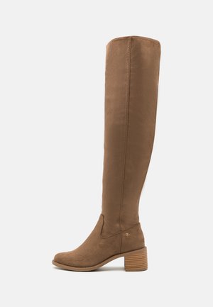 Botte haute jusqu'au genou en suède marron, à talon bloc empilé, avec un logo latéral discret sur un fond clair, vue de profil gauche.