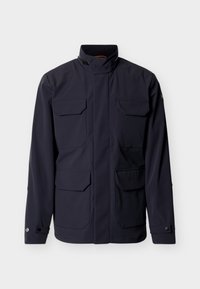 Σκούρο μπλε μπουφάν με ψηλό γιακά, τέσσερις εμπρόσθιες τσέπες με καπάκι και μανσέτες με κουμπιά, εμφανίζεται σε απλό φωτεινό φόντο.