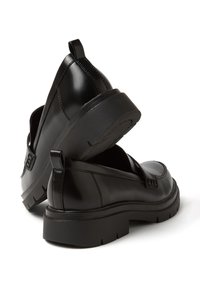 Scarpe slip-on nere in pelle con una finitura liscia, punta arrotondata e una suola in gomma spessa. Presentano un tirante sul retro e dettagli di cucitura discreti.