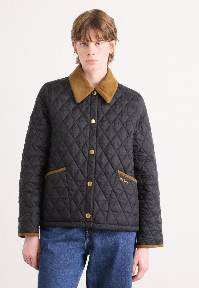 Jachetă neagră matlasată cu guler din catifea maro, nasturi aurii și două buzunare laterale cu o etichetă de marcă brodată.