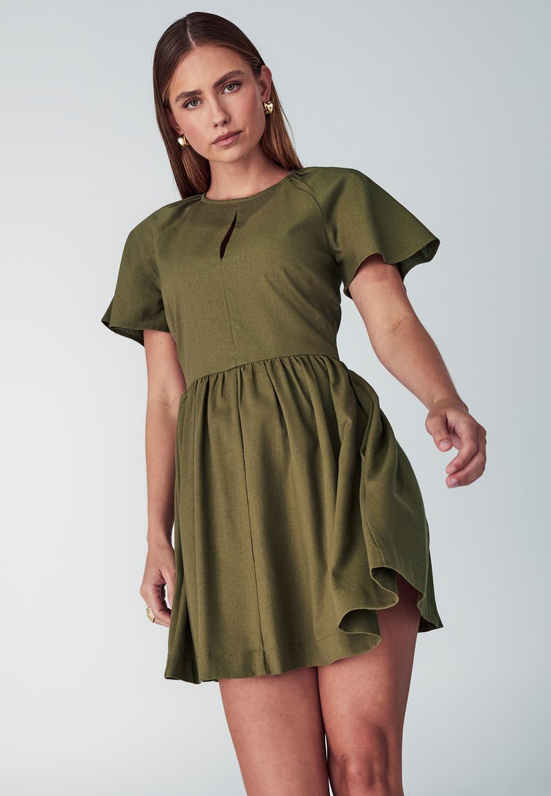 Olive zelena obleka s kratkimi, letečimi rokavi, pasnim šivom in raztegnjeno krilo s čipkastim robom ter majhno odprtino spredaj.