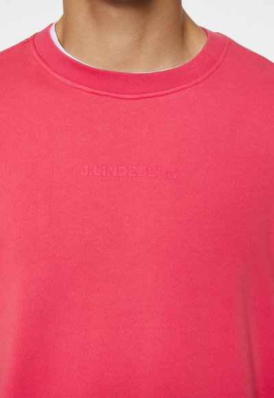 Felpa a girocollo in tessuto rosa brillante. Caratterizzata da logo in rilievo "J.Lindeberg" sulla parte anteriore. Texture liscia con collo a coste.