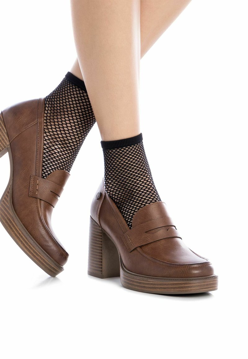 Zapatos de tacón alto de cuero marrón con un tacón cuadrado, con detalles de costura y combinados con calcetas de red negras.