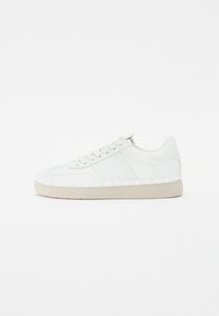 Białe skórzane sneakersy z płaską podeszwą, z tonalnym przeszyciem, sznurowanym przodem i geometrycznymi akcentami wzdłuż podeszwy.