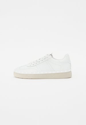 Sneakers bianchi in pelle con suola piatta, caratterizzati da cuciture tono su tono, chiusura con lacci e accenti geometrici lungo la suola.