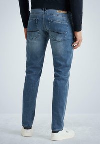 Světle modré džínové kalhoty se slim fit, obsahující dvě zadní kapsy, kontrastní švy a koženou značkovou visačku na pase.