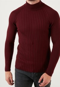 Burgunderfarbener gerippter Rollkragenpullover mit langen Ärmeln und taillierter Form, aus dehnbarem Strickmaterial, mit einem dezenten vertikalen Muster.