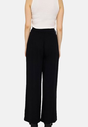 Black wide-leg trousers with a high waist, featuring pleats and a smooth fabric texture, styled with a tucked-in white tank top.