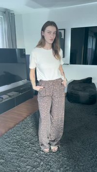Pantalon large à imprimé léopard en marron et beige avec poches avant, associé à un t-shirt blanc simple. Tissu lisse, coupe décontractée.