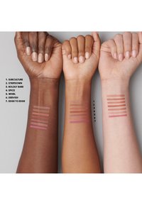 Tre armer med fargeprøver av leppestifter i forskjellige nyanser: dyp brun, medium brun og lys beige, som viser syv horisontale linjer hver.