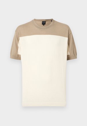 Sweter z krótkim rękawem i okrągłym dekoltem, z beżową górną częścią i rękawami oraz szerokim, kremowym panelem na dole, prezentowany na jednolitym tle.